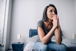 a person sits in bed nervously displaying warning signs of relapse