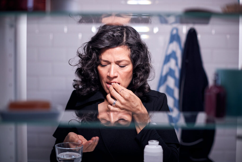 a woman takes her prescribed dose of suboxone to manage her addiction recovery